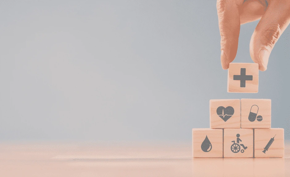 Holzwürfel mit medizinischen Symbolen werden auf einem Tisch von einer Hand übereinander gestapelt
