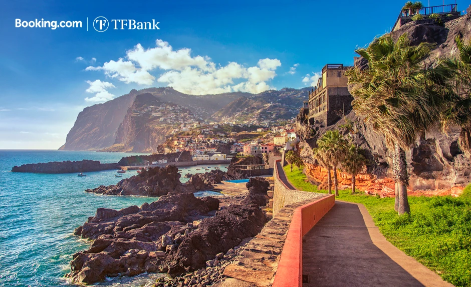 Blick auf einer bergigen Küsten-Stadt mit blauem Wasser und einem Weg entlang des Meers.