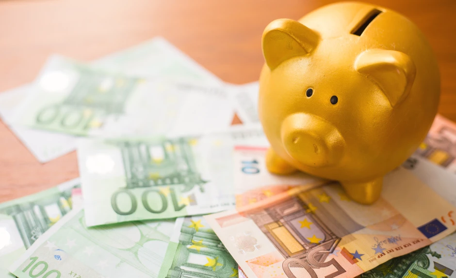 Ein gelbes Sparschwein steht auf 100 € und 50 € Scheinen.
