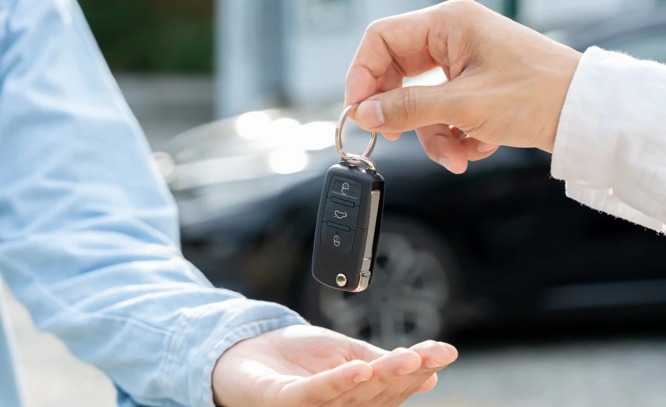 1 Mann reicht einem anderen einen Schlüssel für die Autovermietungin die Hand. TF Bank erklärt
