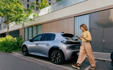 Frau bewegt sich Richtung Auto, um Carsharing-Angebot über Free2move einzulösen.