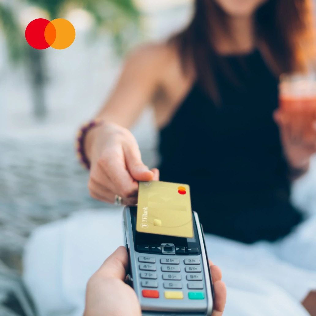 Frau nutzt ihre TF Mastercard Gold zum Bezahlen am Karten Terminal. Links oben sieht man das Mastercard Logo.