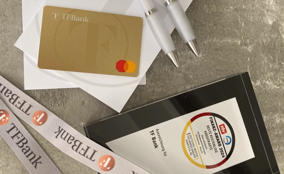 Finanz Award Auszeichnung 2024 der TF Mastercard Gold liegt zusammen mit der Kreditkarte, einem TF Bank Block und Stiften auf einem Tisch.